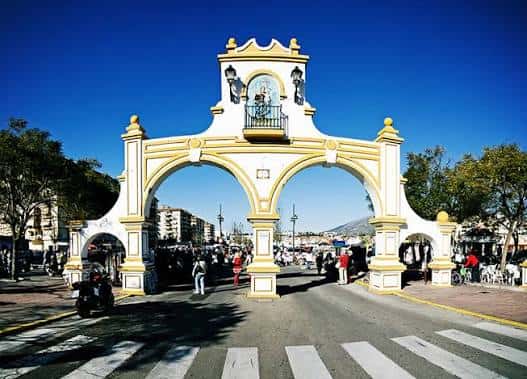 Vista frontal del arco de entrada al Recinto Ferial de Fuengirola con montañas al fondo