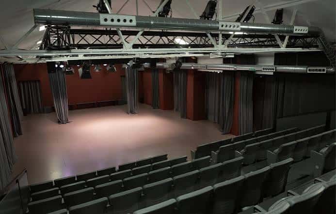 Interior del teatro desde la parte trasera mostrando escenario y cortinas