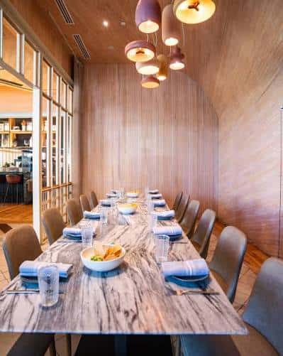 Sala privada con mesa larga de madera y lámparas colgantes