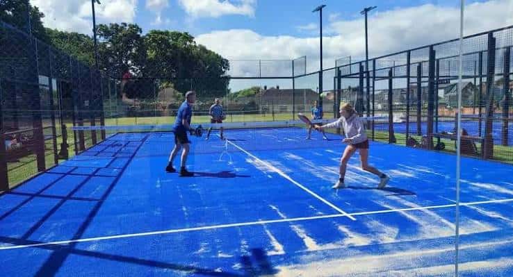 Jugadores de pádel en acción sobre una cancha azul al aire libre