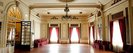 Salón interior con cortinas rojas, suelo de madera y lámpara colgante
