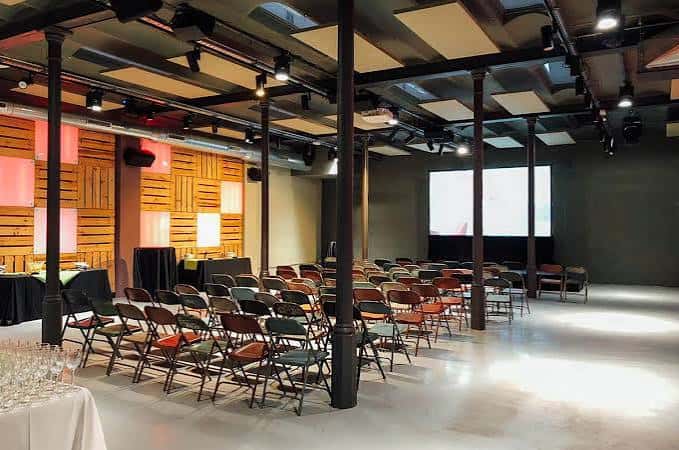 Sala principal del espacio para eventos con disposición de sillas y pantalla