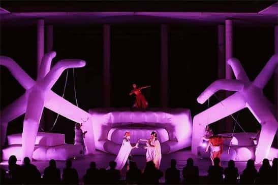 Escenario con actuación teatral y escenografía iluminada en tonos morados