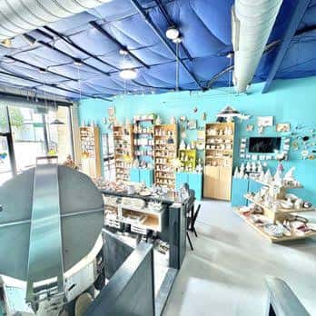 Interior del estudio mostrando mesas de trabajo y estanterías llenas de cerámica