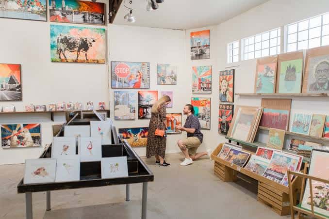 Sala de exposiciones con obras de arte en las paredes y una pareja celebrando un momento especial