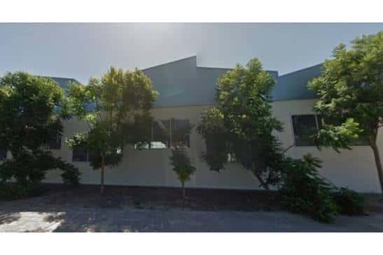 Vista exterior del Pabellón Municipal Angelita Alta con fachada blanca y árboles alrededor