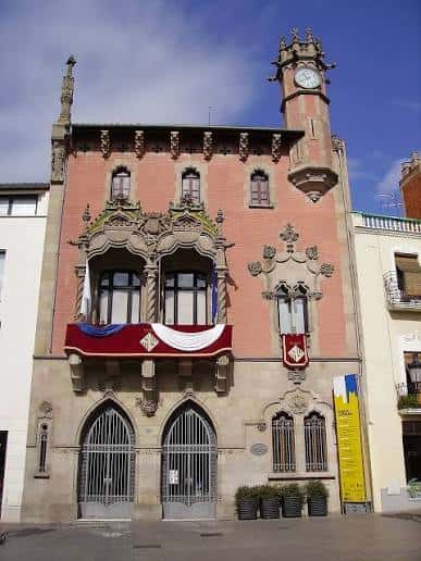Fachada principal del edificio histórico en la plaza, con detalles arquitectónicos y banderas decorativas