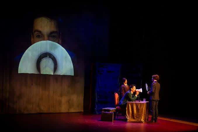 Escenario con representación teatral y proyección de fondo