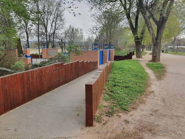 Acceso peatonal al recinto ferial con rampa de madera y entorno natural