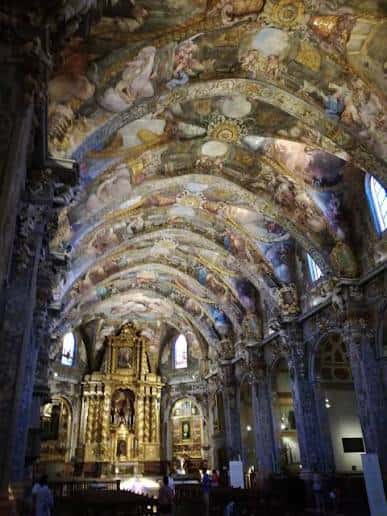 Vista del interior de la iglesia con bóvedas pintadas y retablo dorado