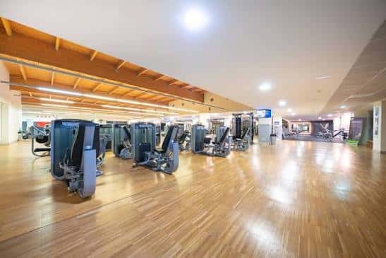 Amplio gimnasio con suelo de madera y equipo de entrenamiento en Forus Fuenlabrada