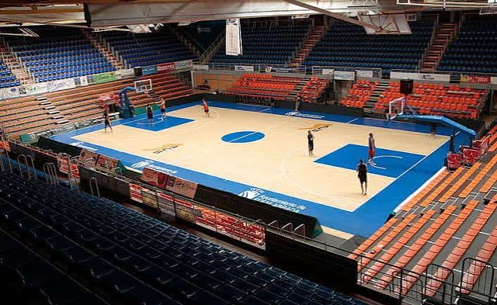 Interior del pabellón con pista de baloncesto y gradas vacías