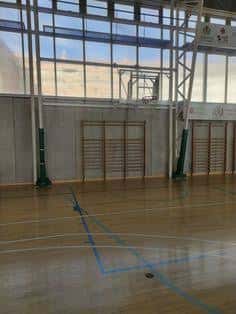 Interior del pabellón mostrando la cancha de baloncesto y canastas
