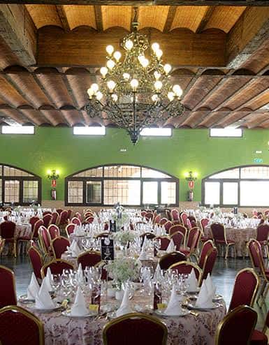 Salón de banquetes decorado para evento con mesas redondas y candelabros