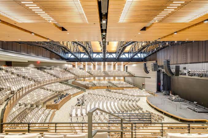Interior del auditorio principal con asientos en gradas y escenario amplio