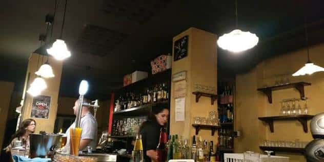 Interior del bar con barra, estanterías de botellas y personal trabajando
