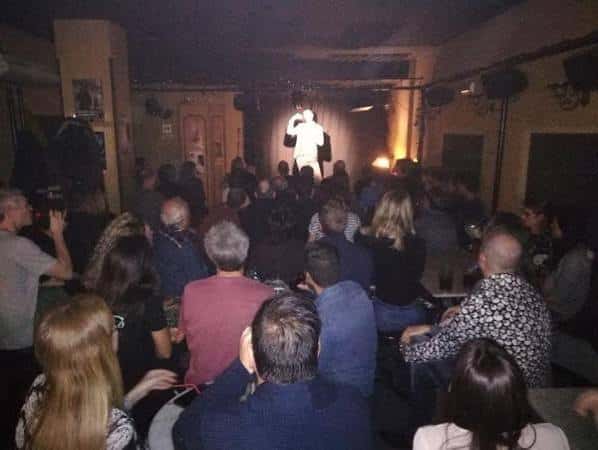Evento en vivo con público sentado frente a un escenario iluminado