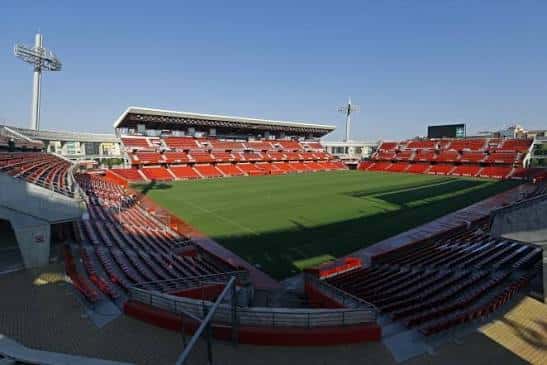 Ángulo amplio del interior del estadio mostrando las tribunas vacías y el terreno de juego