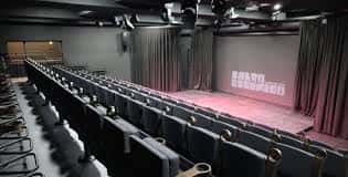 Interior del auditorio mostrando filas de asientos y el telón de fondo