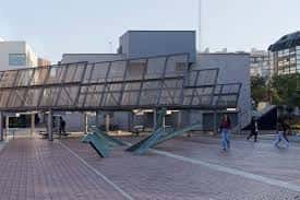 Plaza con personas caminando y elementos escultóricos, mostrando su uso como espacio público dinámico