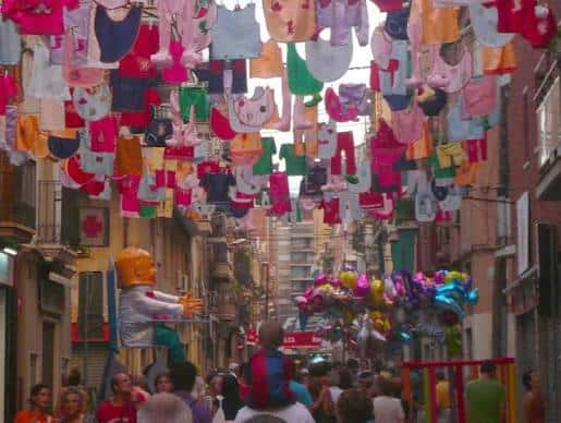 Calle decorada con ropa infantil colgada durante la Festa Major de Sants