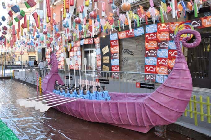 Carroza temática en forma de barco rosa con remos y figuras azules