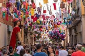 Multitud caminando bajo decoración festiva con globos y prendas colgantes