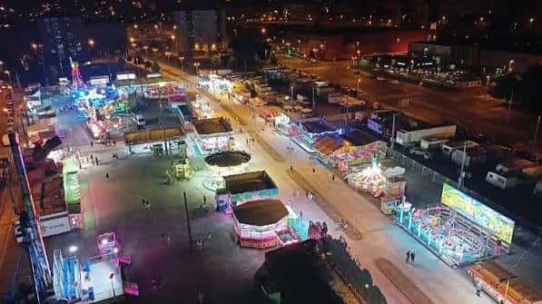 Recinto ferial iluminado por la noche con atracciones y stands decorados