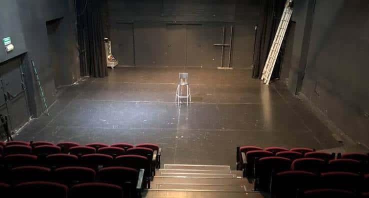 Interior vacío del auditorio con butacas rojas y escenario despejado