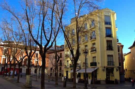 Fachada amarilla de un edificio en la plaza bajo cielo azul despejado