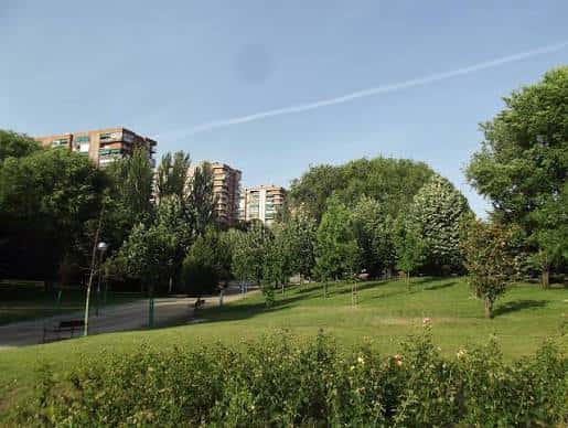 Vista panorámica del parque con zonas verdes y edificios residenciales al fondo