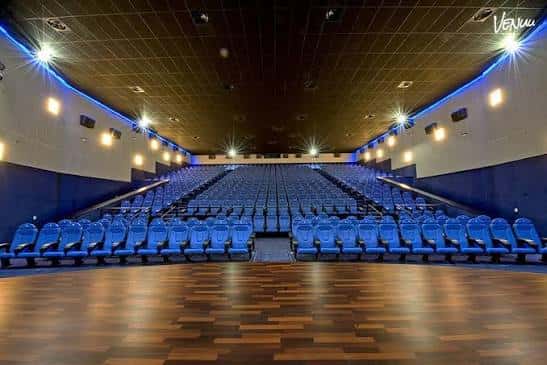 Interior del auditorio con butacas azules y escenario de madera