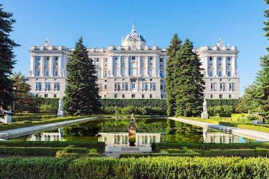 Fachada frontal del Palacio Real reflejada en el estanque de los jardines