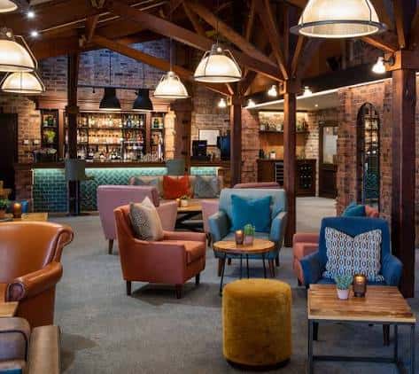 Interior del bar y lounge con decoración moderna, sillones coloridos y vigas de madera expuestas