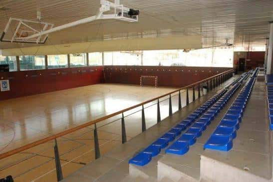 Interior del gimnasio mostrando gradas azules y cancha deportiva