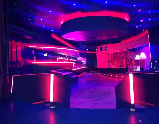 Vista general de la sala de eventos con luces de neón y barra central
