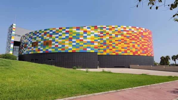 Vista exterior del Palau de la Festa con su característica fachada multicolor y césped en primer plano
