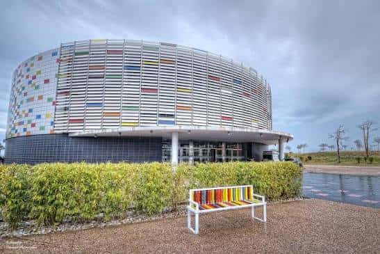 Fachada lateral del edificio con lamas horizontales y banco decorativo frente a él