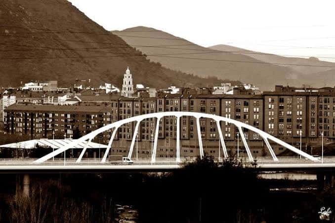 Puente del Centenario con vista de la ciudad y montañas al fondo (tono sepia)
