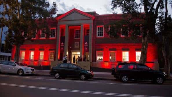 Vista exterior nocturna de la fachada principal del Watt Space Gallery iluminada en rojo