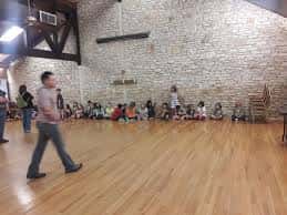 Salón interior con piso de madera y paredes de ladrillo para eventos comunitarios