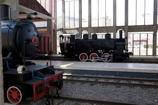 Vista lateral de locomotoras históricas sobre vías dentro del recinto