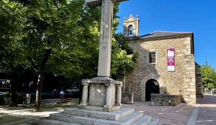 Vista lateral de la Ermita de San Antonio con cruz monumental y árboles frondosos