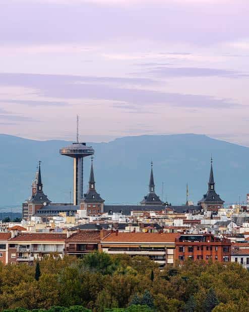 Panorámica del Faro de Moncloa sobre el tejado de la Universidad Complutense con montañas al fondo