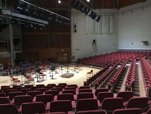 Interior del auditorio con butacas rojas dispuestas para un evento musical o conferencia