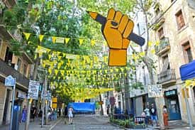 Carrer de Sagunt decorado con banderines amarillos y un gran puño amarillo durante la Festa Major de Sants