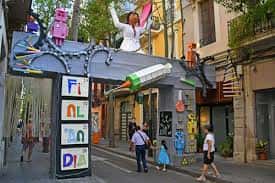 Arco festivo en Carrer de Sagunt con figuras coloridas y letrero 'Festa del Dia'