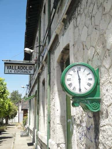 Detalle del reloj verde y cartel de la estación en la fachada