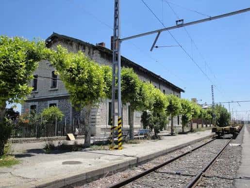 Andén lateral con árboles alineados y estructura de la estación al fondo