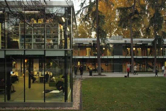 Interior moderno de la biblioteca con estanterías iluminadas y zona de lectura junto a ventanales